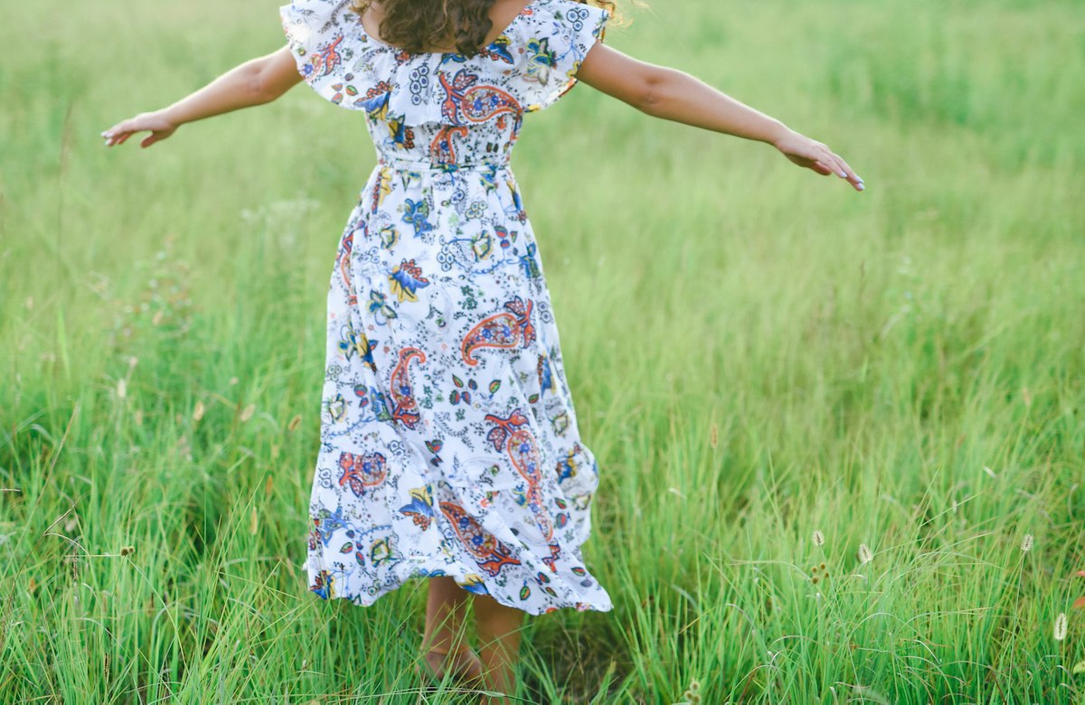 Vestido midi floral branco e azul em um gramado, à luz do dia